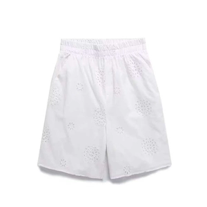 Close-up of white summer shorts featuring intricate eyelet embroidery and elastic waistband