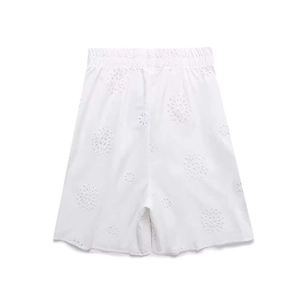 Detail of white hollow-out embroidery shorts featuring elastic waistband and floral patterns