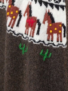 Détail d'un cardigan en maille jacquard avec paysage de montagne et broderie de cactus