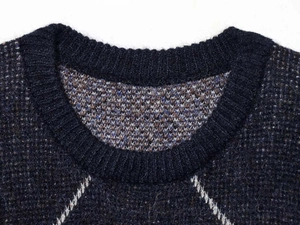 Detail view of navy blue crew neck sweater with textured diamond knit pattern and ribbing