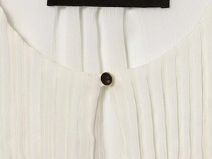 Macro detail of white pleated shirt collar with elegant gold-rimmed button and texture