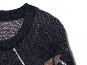 Detailed close-up of dark blue knit sweater showing wool texture and argyle pattern