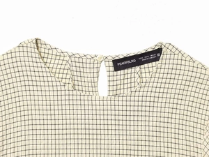 Detailed view of plaid puff sleeve top neckline with teardrop button closure