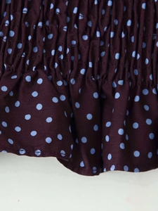 Vue détaillée du tissu à pois marron foncé avec smocks élastiques et ourlet à volants
