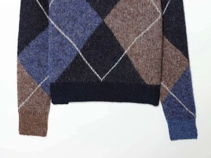 Close-up of knit fabric showing blue and brown argyle pattern and ribbed hem texture