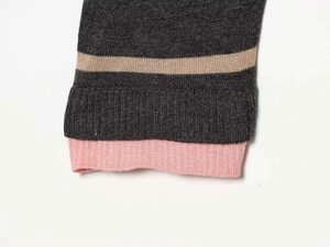 Detailed view of dark grey knit sweater cuff with gold stripe and pink ribbed trim
