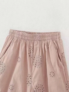 Detail of pink embroidered shorts featuring elastic waistband and floral cut-out patterns