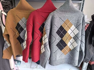Detailansicht der Rautenmuster-Pullover in Karamell, Rot und Grau mit Rippbündchen