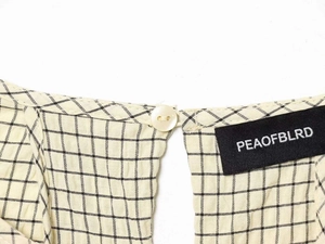 Close-up of the black and white gingham pattern neckline with a cream button and logo label
