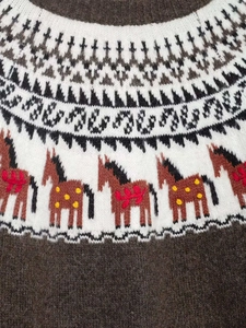 Détail macro du motif tricoté Fair Isle avec des chevaux décoratifs sur pull marron
