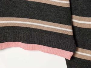 Close-up of the striped knit sweater hem with pink ribbed cuffs and high-quality fabric texture