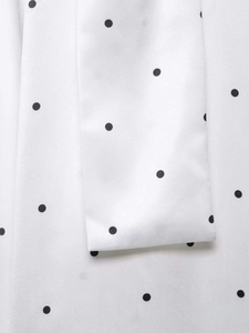 Vue détaillée d'une blouse en mousseline blanche à pois noirs avec nœud papillon