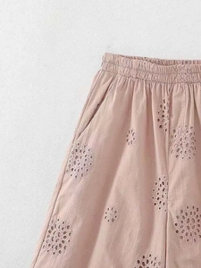 Detail of dusty pink shorts with elastic waist and delicate eyelet embroidery textures