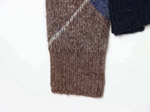 Close-up of diamond pattern knit sweater showing ribbed cuffs and wool blend texture