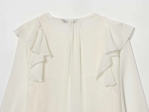 Close-up of white chiffon blouse with layered ruffle details and round neckline