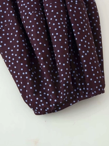Détail du tissu bordeaux à pois bleu clair montrant la texture et les coutures fines
