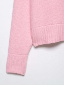 Detailed close-up of ribbed cuffs and hem on a premium pink knit sweater for women