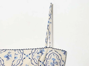 Dettaglio dell'abito estivo a fiori blu con scollo in pizzo a onde e spalline sottili