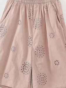 Detail of dusty pink elastic waist shorts with intricate circular cutout embroidery