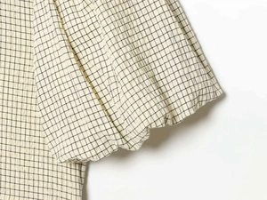 Detail of puffed sleeve with elastic cuff in beige and black checkered seersucker fabric