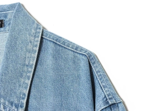Detailed close-up of collar and shoulder seams on light blue washed denim jacket
