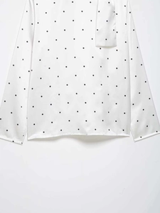 Vue détaillée du chemisier en satin blanc à pois noirs avec détail de cravate