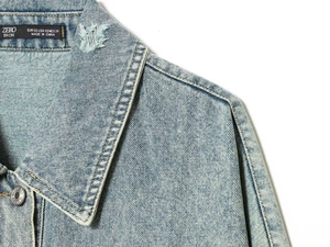 Dettaglio colletto giacca denim celeste con etichetta e spalla con effetto strappato