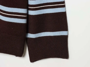 Dettaglio delle maniche in maglia a righe marrone scuro e blu chiaro con polsini a coste