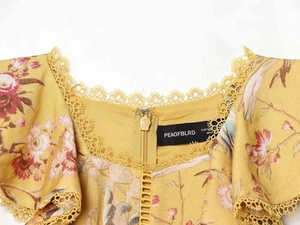 Dettaglio dell'abito floreale giallo con scollo in pizzo e stampa a fiori delicata