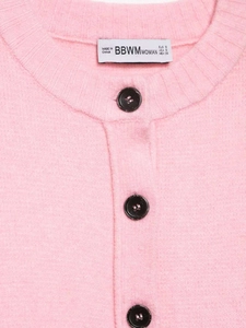 Detail of pink knit cardigan showing round black buttons and soft fabric texture