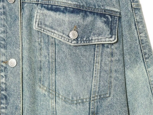 Macro di una giacca in denim azzurro con tasca a patta e bottoni metallici incisi jeans