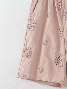 Detailed view of pale lotus pink shorts featuring delicate floral eyelet embroidery patterns