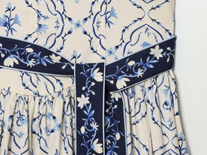 Dettaglio di un abito estivo con stampa floreale blu e cintura annodata in vita