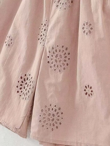 Close-up of pink cotton fabric with intricate eyelet embroidery and hollow-out patterns