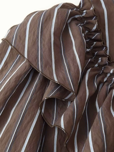 Détail du tissu rayé marron avec bords à volants et fines rayures verticales bleu-blanc