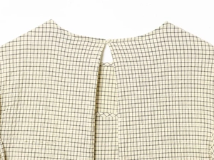 Detail view of the back neckline with teardrop cutout and button on plaid top