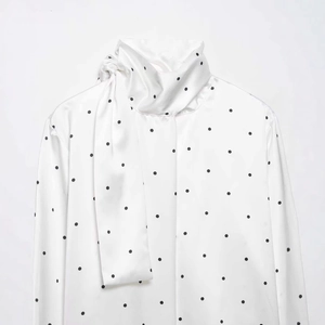 Élégante blouse en satin blanc à pois noirs avec manches longues et nœud papillon au col