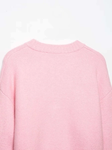 Detail of the crew neckline and ribbed texture on this soft pink knit sweater