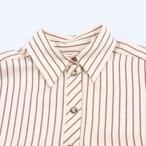 Detalle del cuello de una camisa a rayas con cuello en punta y botones de carey