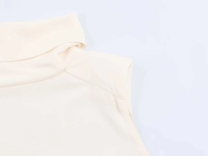 Detailed view of the layered high neck and fine knit texture of this beige sleeveless top