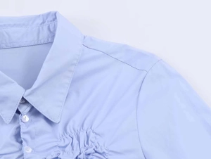 Detail of light blue poplin shirt featuring pleated texture and buttoned collar