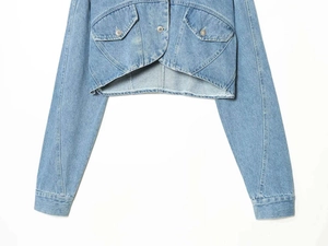 Detail of short denim jacket featuring unique curved hem and washed light blue finish