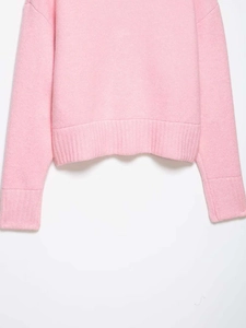 Detail of pink knit sweater featuring ribbed cuffs and hem for a comfortable fit