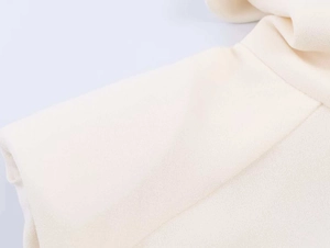 Detailed close-up showing the textured cream fabric and seam of the sleeveless vest
