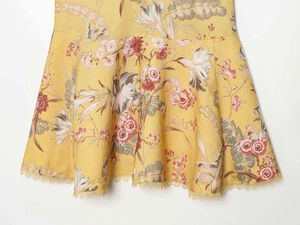Dettaglio dell'orlo del vestito giallo con pizzo delicato e motivi floreali vintage