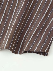 Gros plan sur la texture du tissu rayé et les coutures de l'ourlet de cette chemise