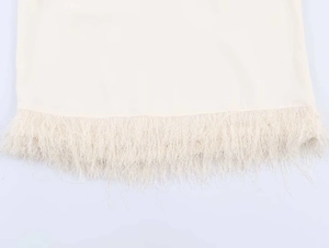 Detailed macro view of delicate cream-colored top with elegant feather fringe hemline