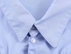 Detail shot of a light blue stretch poplin shirt showing the collar and pearl buttons