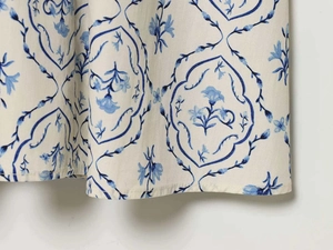 Dettaglio della stampa floreale blu vintage su abito beige a portafoglio con trama