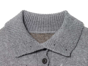 Detail eines grauen Rauten-Strickpullovers mit Rippkragen und Kontrast-Jacquardfutter